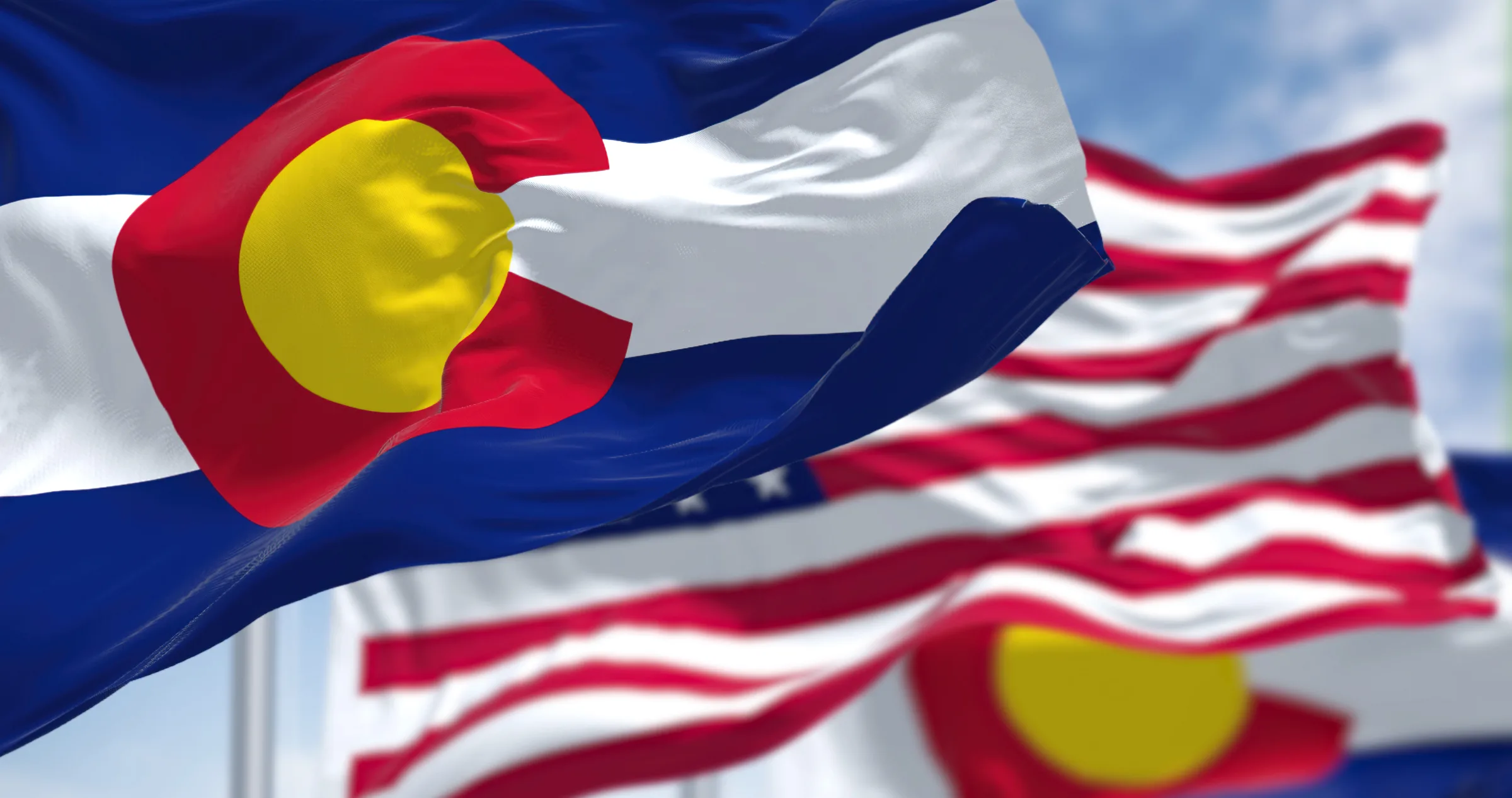 Colorado and U.S. flags against a clear sky